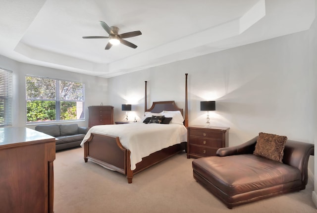 carpeted bedroom with a tray ceiling and ceiling fan