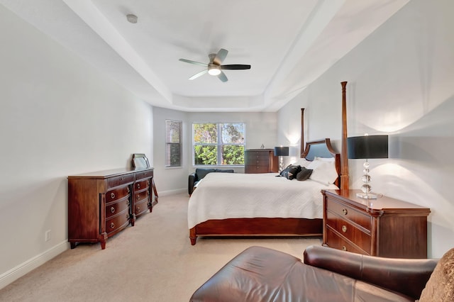 carpeted bedroom featuring a tray ceiling and ceiling fan