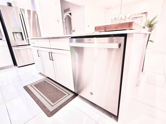 kitchen with stainless steel appliances, pendant lighting, light tile patterned floors, white cabinets, and a center island