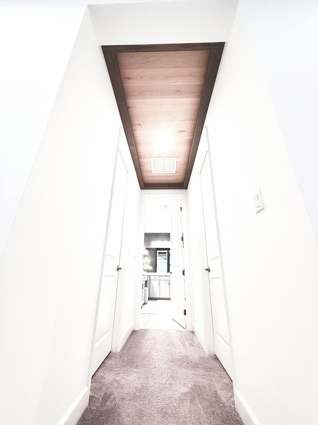 corridor with a skylight, wooden ceiling, and light colored carpet