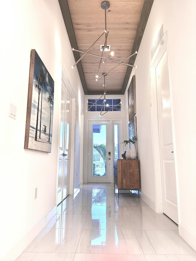 doorway to outside with light tile patterned flooring, an inviting chandelier, and wood ceiling