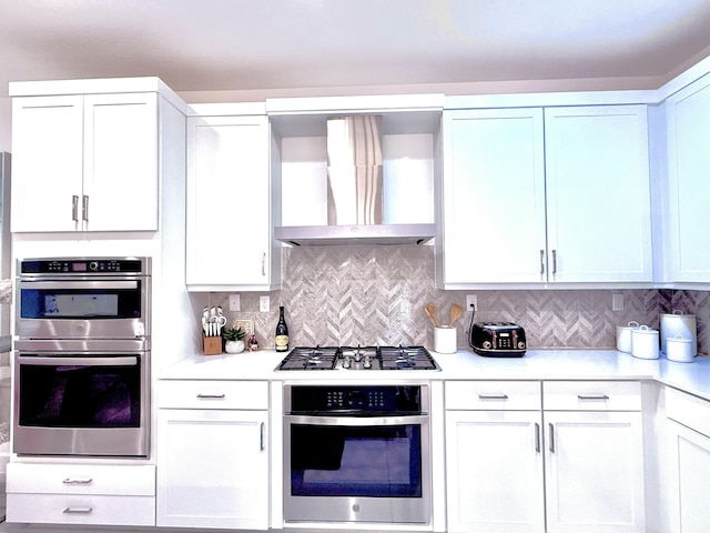 kitchen featuring white cabinets, backsplash, wall chimney range hood, and stainless steel appliances