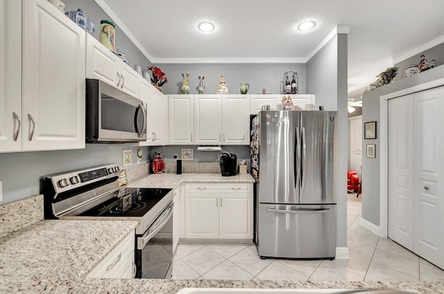 kitchen featuring crown molding, light tile patterned floors, appliances with stainless steel finishes, white cabinetry, and light stone countertops