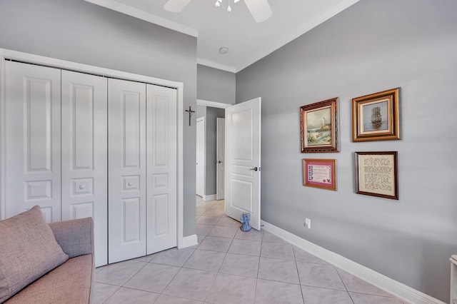 unfurnished bedroom featuring light tile patterned floors, a closet, ornamental molding, a ceiling fan, and baseboards