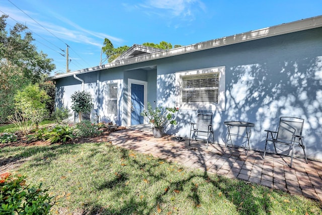 back of house with a patio area, a yard, and stucco siding