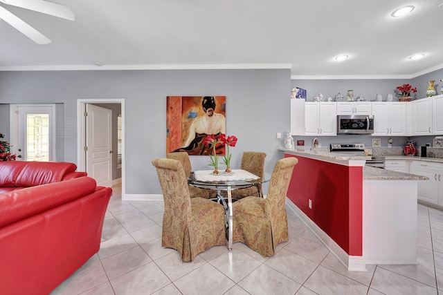 kitchen featuring light tile patterned floors, white cabinets, appliances with stainless steel finishes, a breakfast bar area, and ornamental molding