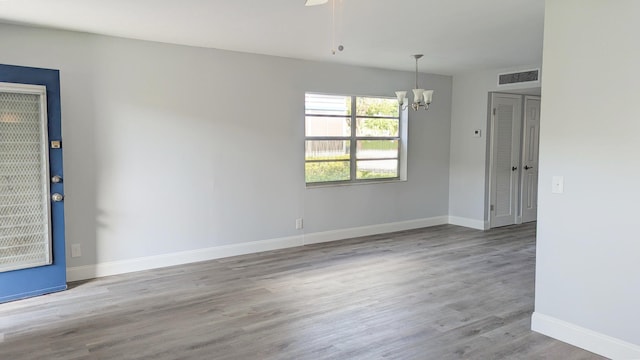 unfurnished room with a chandelier and light wood-type flooring