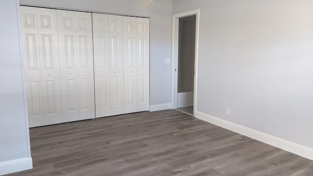 unfurnished bedroom featuring a closet and dark wood-type flooring