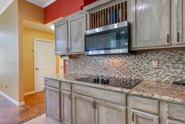 kitchen with decorative backsplash, light stone countertops, and black electric cooktop