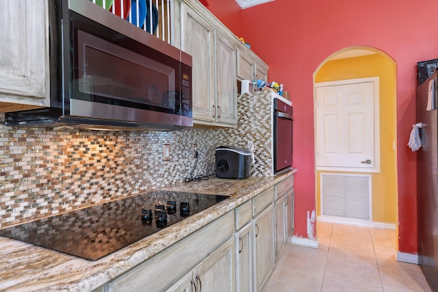 kitchen with black appliances, decorative backsplash, light stone counters, and light tile patterned floors