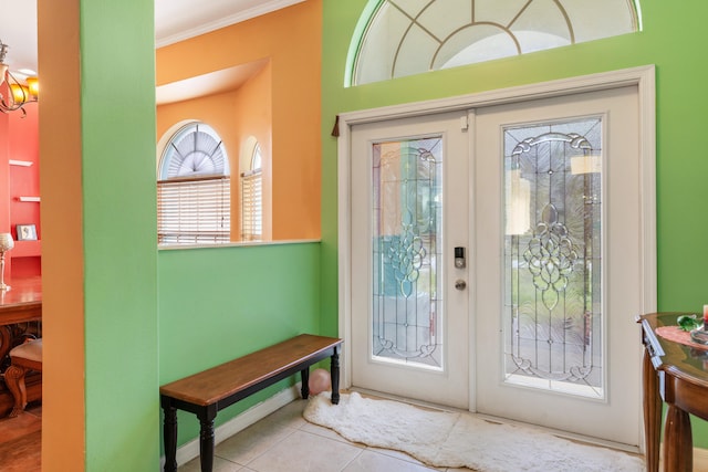 entryway with french doors, light tile patterned floors, ornamental molding, and a notable chandelier