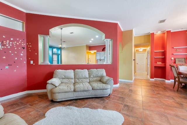 tiled living room with decorative columns, ornamental molding, sink, and a chandelier