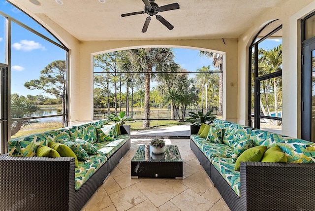 sunroom featuring ceiling fan and a water view