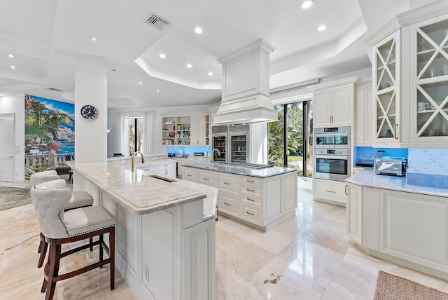 kitchen with sink, a raised ceiling, appliances with stainless steel finishes, and a spacious island