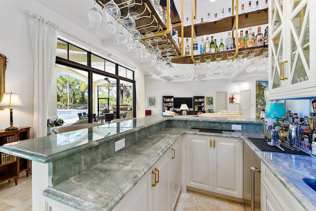 kitchen featuring coffered ceiling, kitchen peninsula, light stone countertops, white cabinets, and beamed ceiling