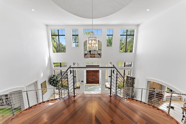 foyer with a towering ceiling, hardwood / wood-style flooring, and a chandelier