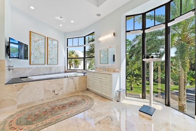 bathroom featuring tiled tub and vanity