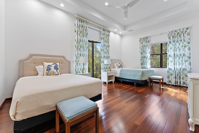 bedroom with a raised ceiling, ceiling fan, and dark hardwood / wood-style floors