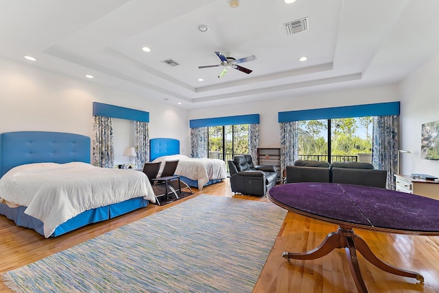 bedroom featuring hardwood / wood-style flooring, ceiling fan, and a tray ceiling