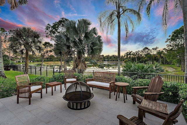 patio terrace at dusk featuring a fire pit and a water view