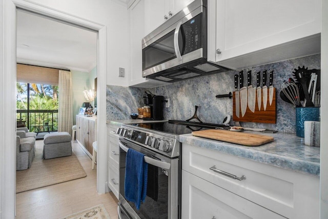 kitchen with white cabinetry, stainless steel appliances, crown molding, and decorative backsplash