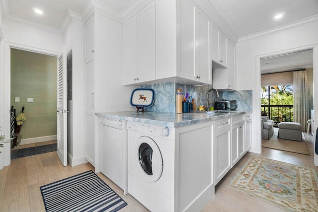 laundry area with crown molding, light hardwood / wood-style flooring, cabinets, and washing machine and clothes dryer