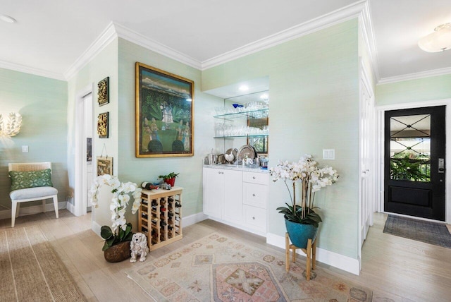 bar featuring white cabinetry, ornamental molding, sink, and light hardwood / wood-style flooring