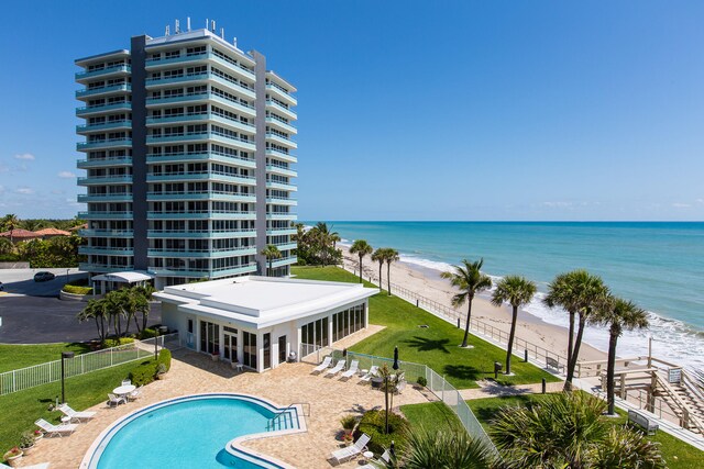 view of pool with a patio area, a water view, and a view of the beach