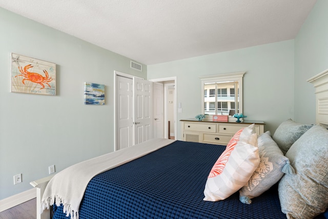 bedroom with a textured ceiling, hardwood / wood-style flooring, and a closet