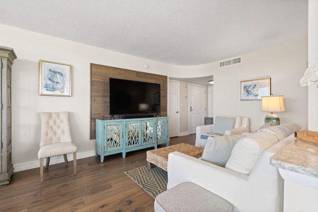 living room with a textured ceiling and dark hardwood / wood-style floors