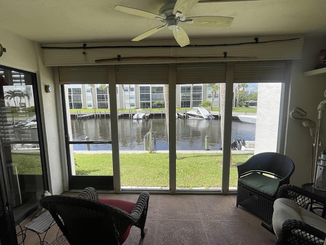 sunroom / solarium with ceiling fan and a water view