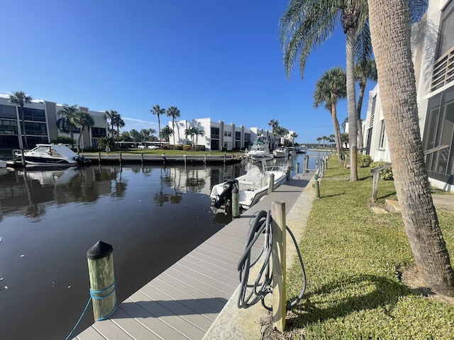 view of dock with a yard and a water view