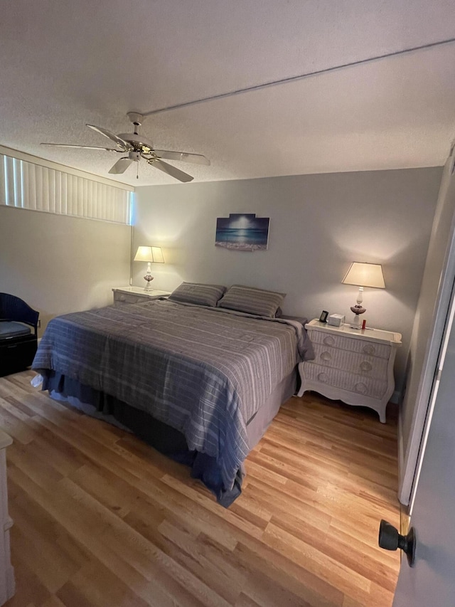 bedroom with ceiling fan, wood-type flooring, and a textured ceiling