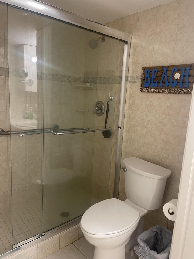 bathroom featuring tile patterned floors, an enclosed shower, tile walls, and toilet