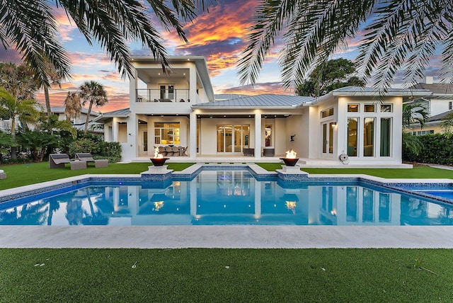 pool at dusk featuring outdoor lounge area, ceiling fan, and a patio