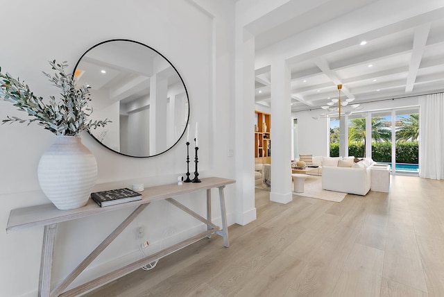 hallway with beam ceiling, an inviting chandelier, light hardwood / wood-style flooring, and coffered ceiling