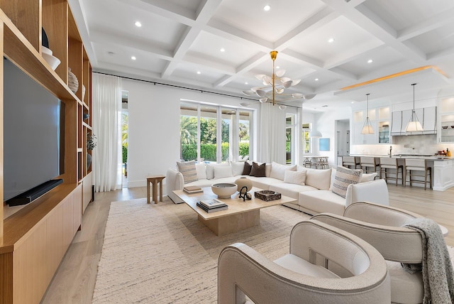 living room with beam ceiling, light hardwood / wood-style floors, coffered ceiling, and a notable chandelier