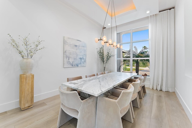 dining room with light wood-type flooring and a tray ceiling