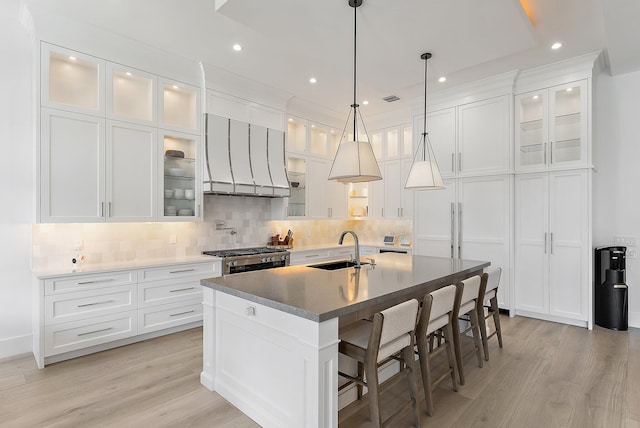 kitchen featuring a center island with sink, white cabinetry, sink, and stainless steel range with gas stovetop