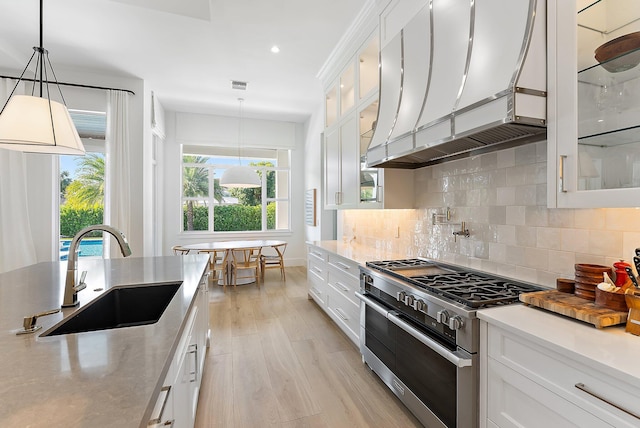 kitchen featuring white cabinetry, high end stove, and sink