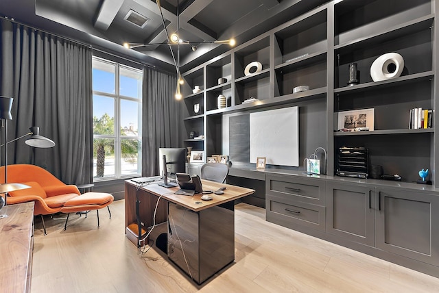 office featuring light wood-type flooring, coffered ceiling, built in desk, built in features, and beamed ceiling