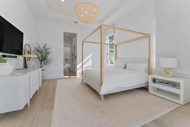 bedroom with a raised ceiling and light hardwood / wood-style floors