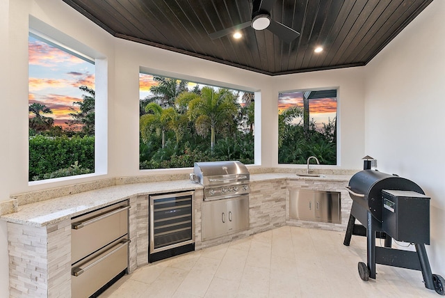 patio terrace at dusk with ceiling fan, sink, exterior kitchen, wine cooler, and grilling area