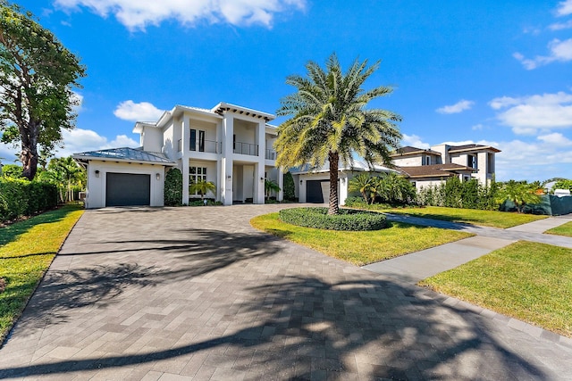 view of front of home with a balcony, a front lawn, and a garage