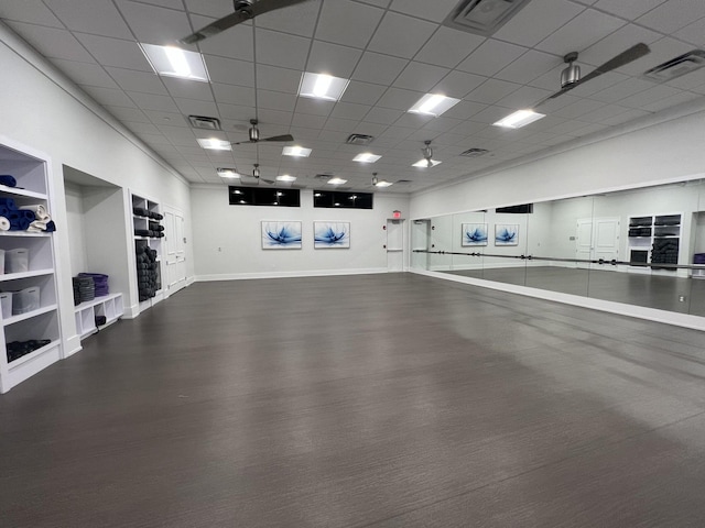 interior space featuring a paneled ceiling, ceiling fan, and built in shelves