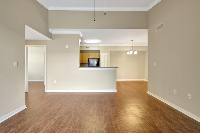 unfurnished living room featuring a high ceiling, a chandelier, dark hardwood / wood-style floors, and ornamental molding