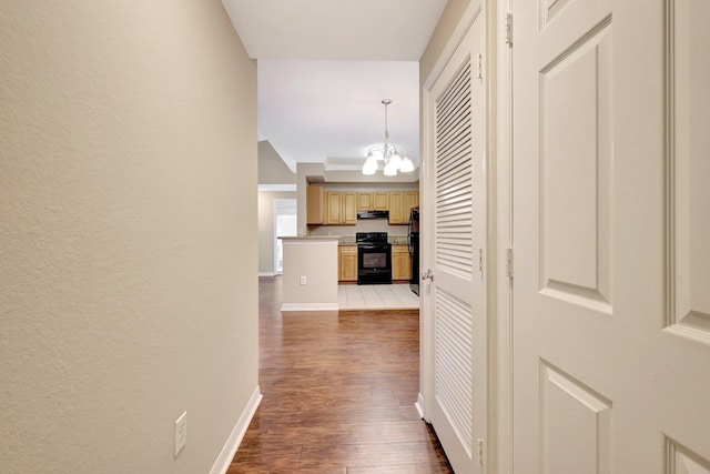 hall with hardwood / wood-style flooring and a notable chandelier