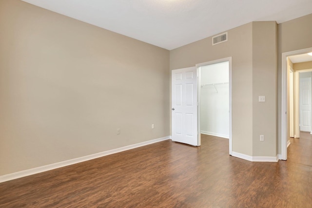 unfurnished bedroom with a walk in closet, dark hardwood / wood-style flooring, and a closet