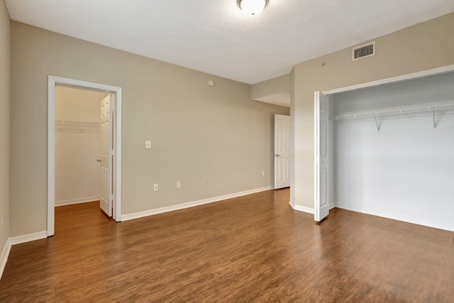 unfurnished bedroom with dark hardwood / wood-style flooring, a textured ceiling, and a closet