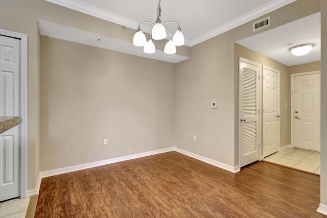 unfurnished dining area with a notable chandelier, wood-type flooring, and crown molding